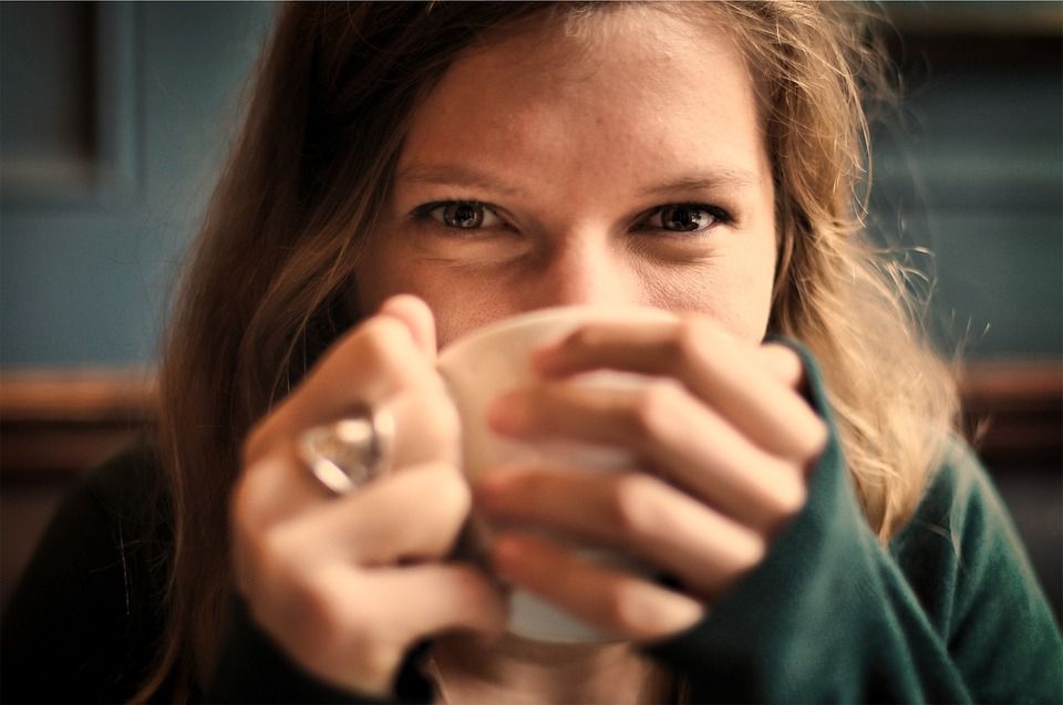 Lächelnde junge Frau trinkt aus Teetasse