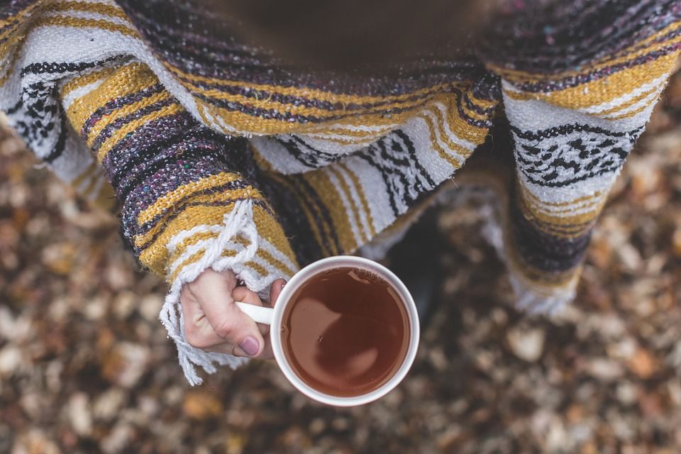 Frau in warmer Kleidung hält Teetasse