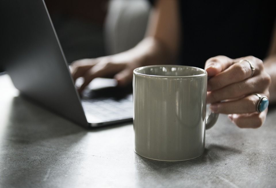 An Laptop sitzende Person mit Teetasse