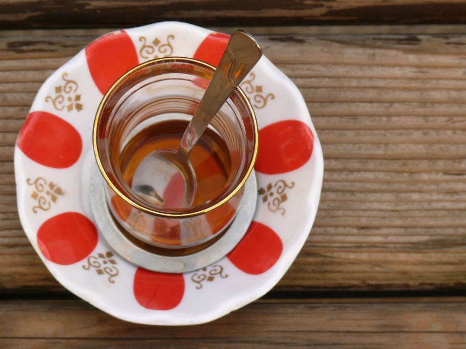 Teeglas mit Teelöffel auf Unterteller