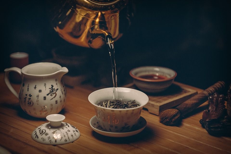 Tee wird aus Teekanne in Teetasse gegossen