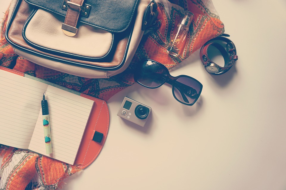 Rucksack mit Sonnenbrille, Kamera und Notizbuch